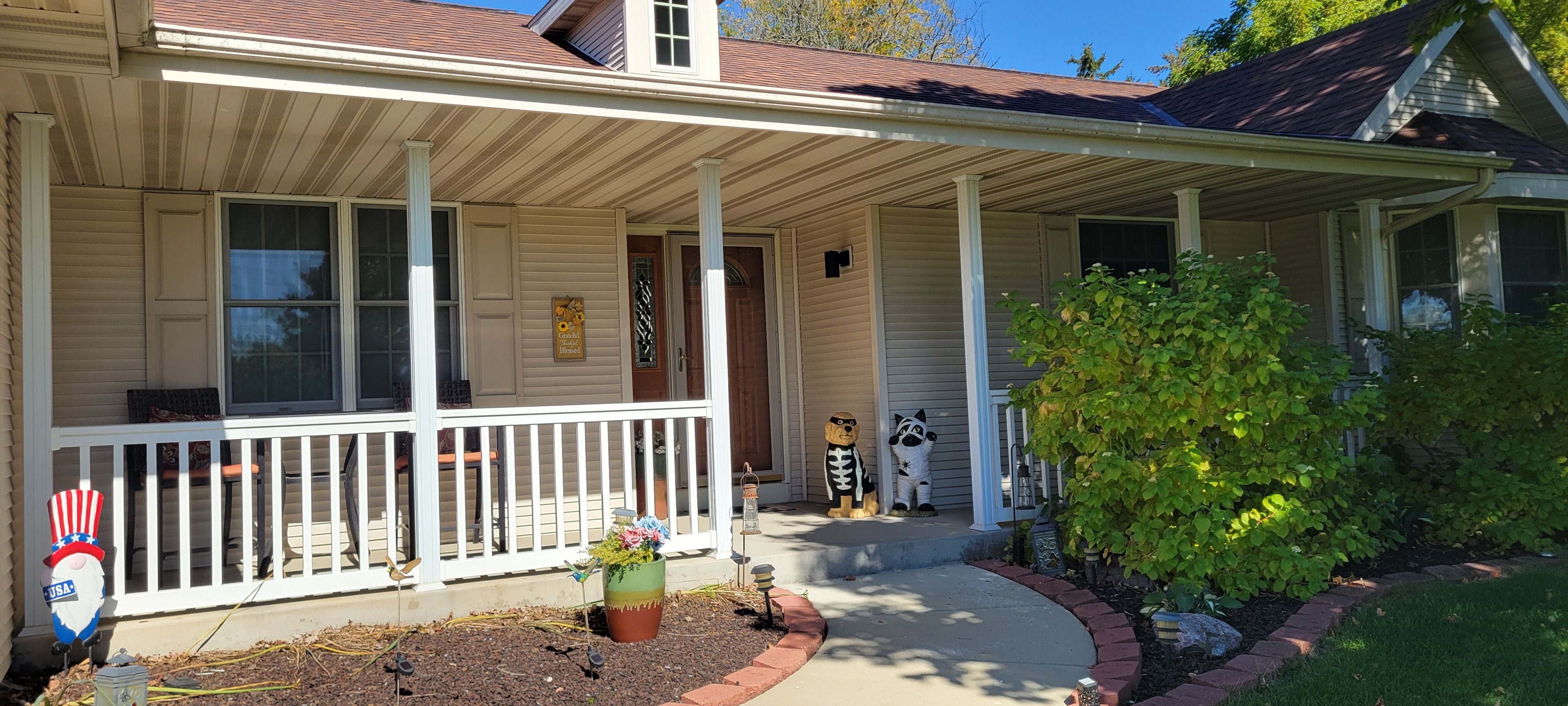 A house with a covered porch, a mailbox, and a small garden with a bird feeder.