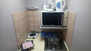 Een kleine keuken met een magnetron, koffiezetapparaat en een afdruiprek.