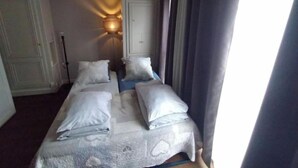 Een hotelkamer met twee bedden, een nachtkastje, een lamp en een deur.