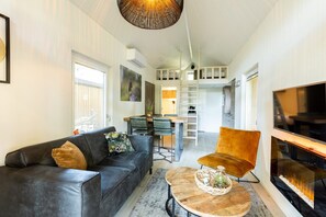 Relax in a cozy living space with a black leather sofa, round coffee table, and vibrant armchair.