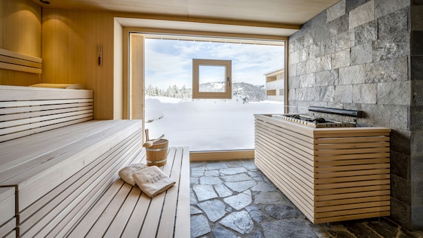 Un sauna con bancos de madera, suelo de piedra y pared de piedra.