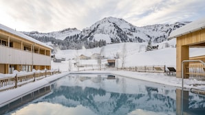 Paisaje montañoso nevado con una piscina que refleja el entorno.