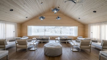 Relax in this stylish space with a central round ottoman, sofas, and armchairs arranged around a coffee table.