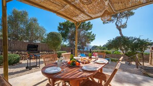 Un espace de restauration en plein air avec une table et des chaises en bois, entouré d’une pergola.