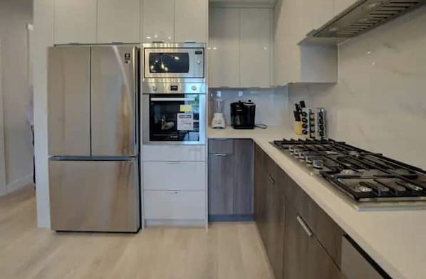 Une cuisine moderne équipée d’un réfrigérateur en acier inoxydable, d’un four encastré et d’une cuisinière  à gaz.