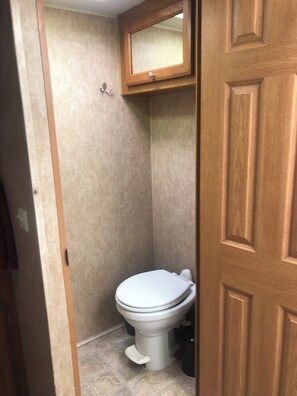 Bathroom features a toilet and a cabinet above, with a textured wallpaper and tiled floor.