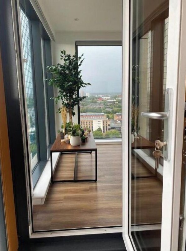 Enjoy the city view from this balcony with a small table and potted plants.