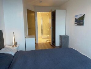 Cozy retreat with a single bed, bedside table, and wardrobe, offering a functional layout and glass-enclosed shower.