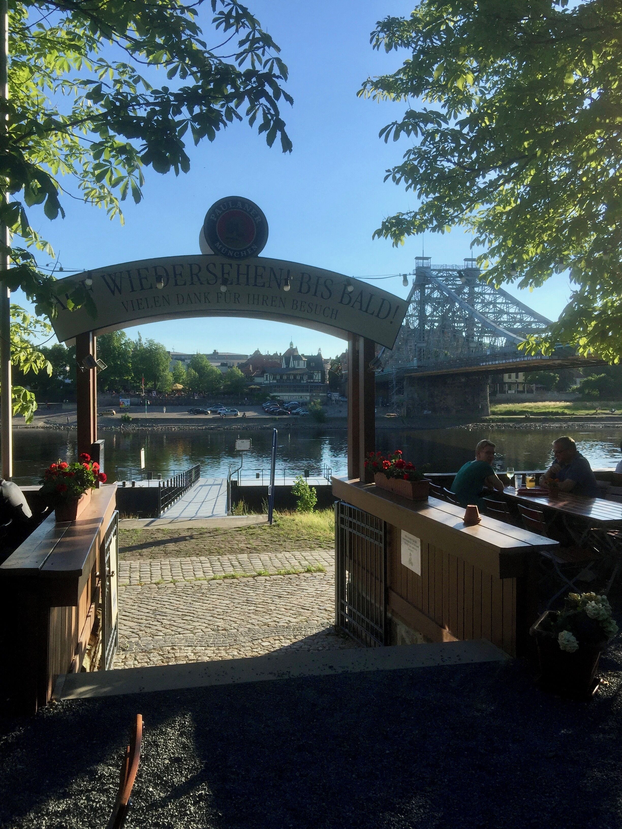 Eine Bar am Flussufer, mit einem Schild, auf dem steht: "WIEDERSEHEN BIS BALTH! VIELEN DANK FÜR IHREN BESUCH".