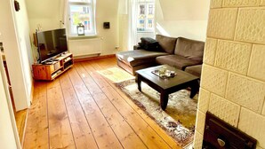 Een woonkamer met een houten vloer, een bank, een salontafel en een televisie.