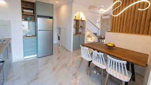 Een moderne keuken met een ingebouwde vaatwasser, een houten eettafel met stoelen, en een trap naar een verdieping.