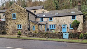 A stone building with multiple windows and a blue door. - Rose Cottage - Cosy Cottage in Millers Dale (Buxton)