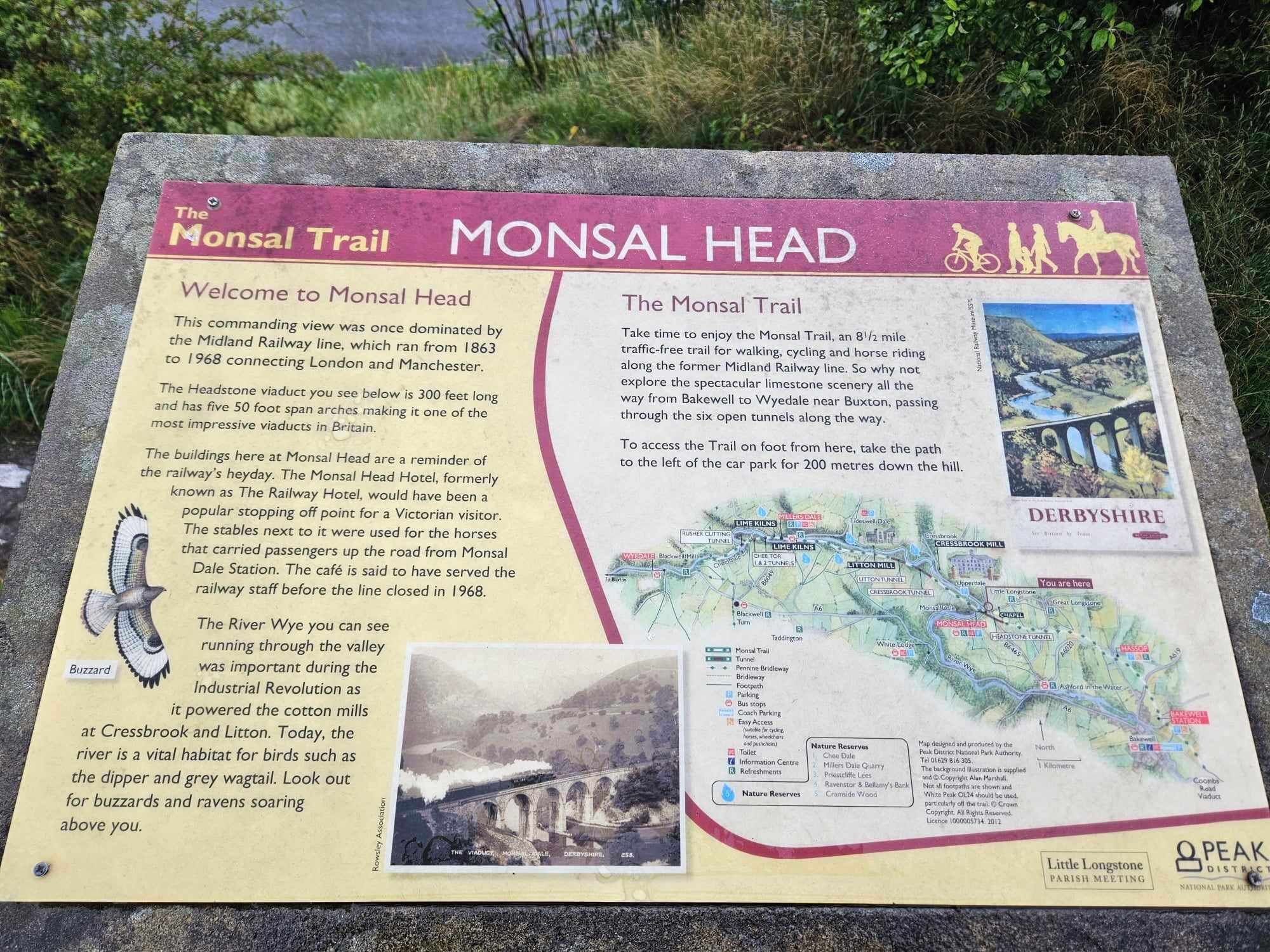 A historical sign at Monsal Head detailing the Monsal Trail, including a map and information about the area's past railway use and natural features.