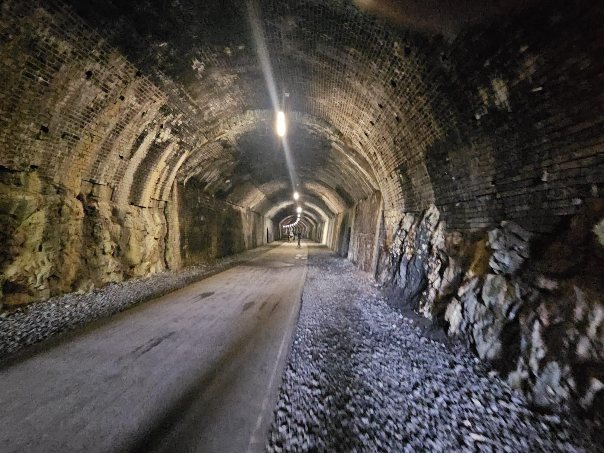 A tunnel with brick walls and a gravel path.