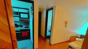 A hotel room with a wooden floor, a small kitchen area with a microwave, and a dining area with a table and chairs. - Unbeatable Quality and near to the forest ! (Bogotá)