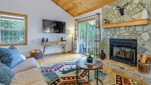Una sala de estar acogedora con chimenea de piedra, un ventanal grande y un sofá cómodo.