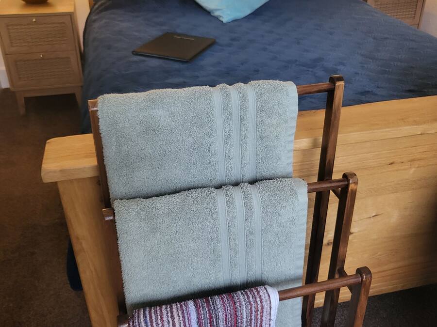 A wooden bed with a blue bedspread and a single pillow, flanked by two bedside tables with lamps.
