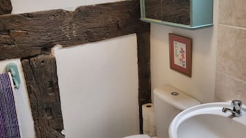 Een badkamer met een wit toilet, een wastafel, een spiegel en een handdoekhouder.