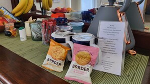 Una presentación de desayuno con tetera, bolsitas de té, café, fruta y aperitivos envasados.