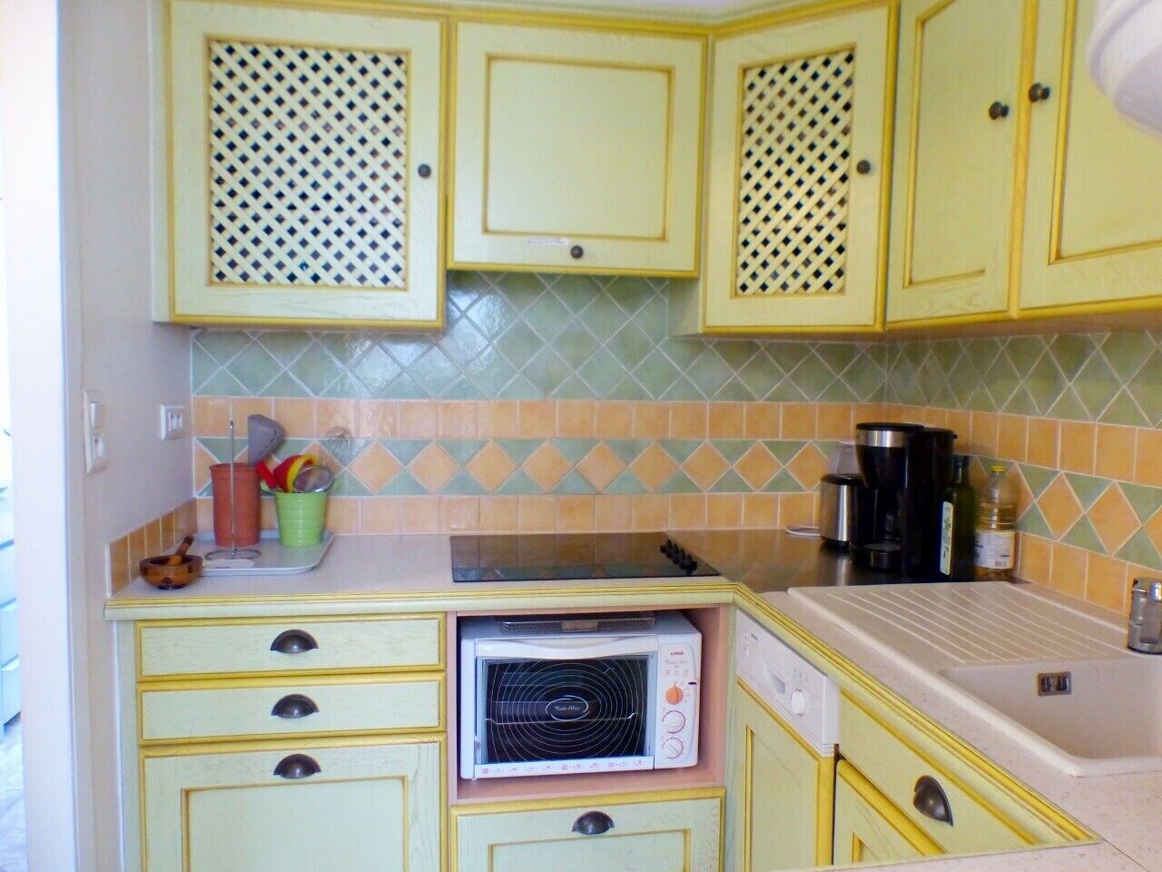 A kitchen with yellow cabinets, a microwave, and a coffee maker.