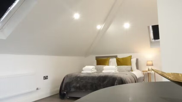 Een moderne slaapkamer met een bed, bedlampen en een aan de muur bevestigde televisie.