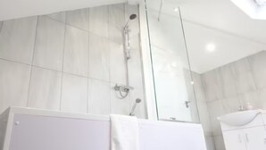 Een moderne badkamer met een douchecabine van glas, een witte wastafel en een grote spiegel.