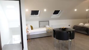 Een moderne hotelkamer met een bed, een klein tafeltje, twee stoelen, een nachtkastje en een raam met uitzicht.