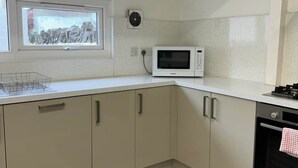 Une cuisine équipée d’un four à micro-ondes, d’un four traditionnel et d’une fenêtre donnant sur un immeuble.