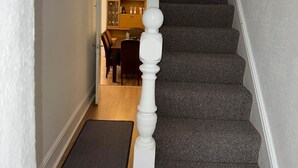 Un escalier avec des marches recouvertes de moquette et une balustrade blanche.