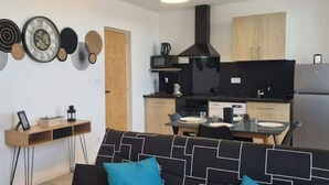 Ein kompakter Wohnbereich mit Küchenzeile, Essplatz und einer Sitzecke mit Sofa und kleinem Tisch.