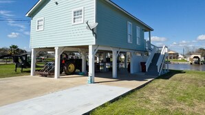 A light blue two-story house with a covered porch and a staircase leading to the upper level. - Creekside Getaway perfect for a relaxing weekend of fishing on the creek! (Sargent)