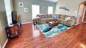 A living room with a sectional sofa, a coffee table, and a TV stand. - Creekside Getaway perfect for a relaxing weekend of fishing on the creek! (Sargent)