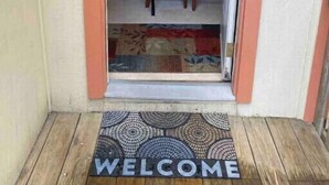 A doorway leading into a room with a dining table and chairs, a laptop on the table, and a welcome mat at the entrance. - The Treehouse
 (Dayton)