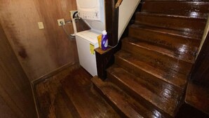 A wooden staircase leading to a laundry room with a washing machine and a small table with cleaning supplies. - The Treehouse
 (Dayton)