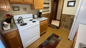 A compact kitchen with wooden cabinets, a white stove, and a refrigerator. - The Treehouse
 (Dayton)