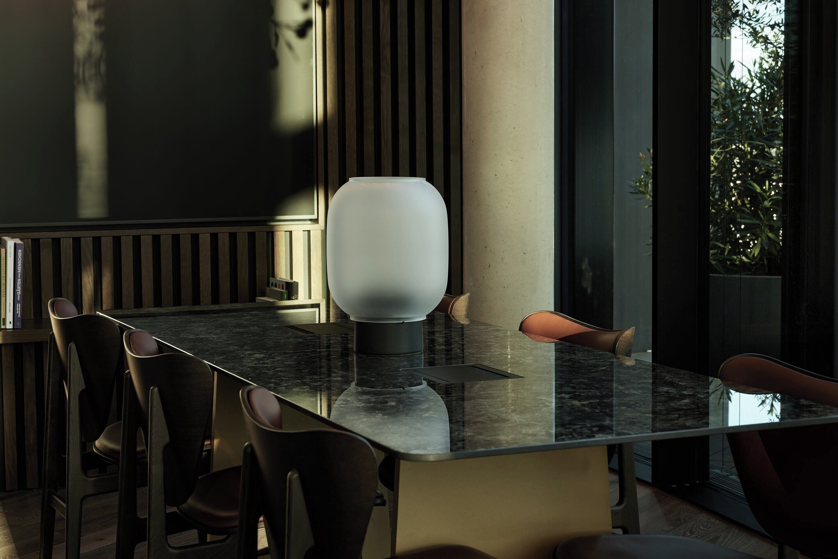 Un comedor moderno con una mesa de mármol, sillas oscuras y una lámpara blanca original.