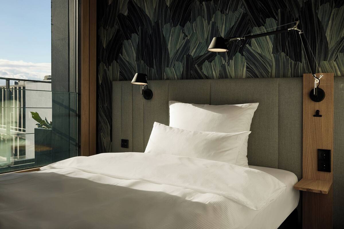 A modern bedroom with a large bed, a view of the sky, and a unique wall design.