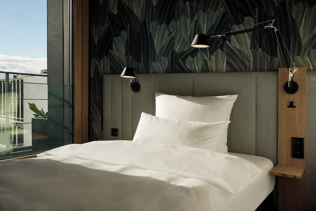 Un dormitorio moderno con una cama grande, vistas al cielo y un diseño de pared original.