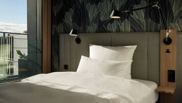 A modern bedroom with a large bed, two wall-mounted lamps, and a view of the sky through a balcony.