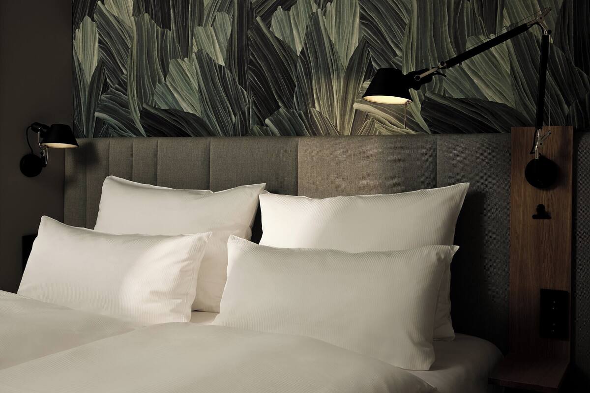 A neatly made bed with white linens and two bedside lamps.