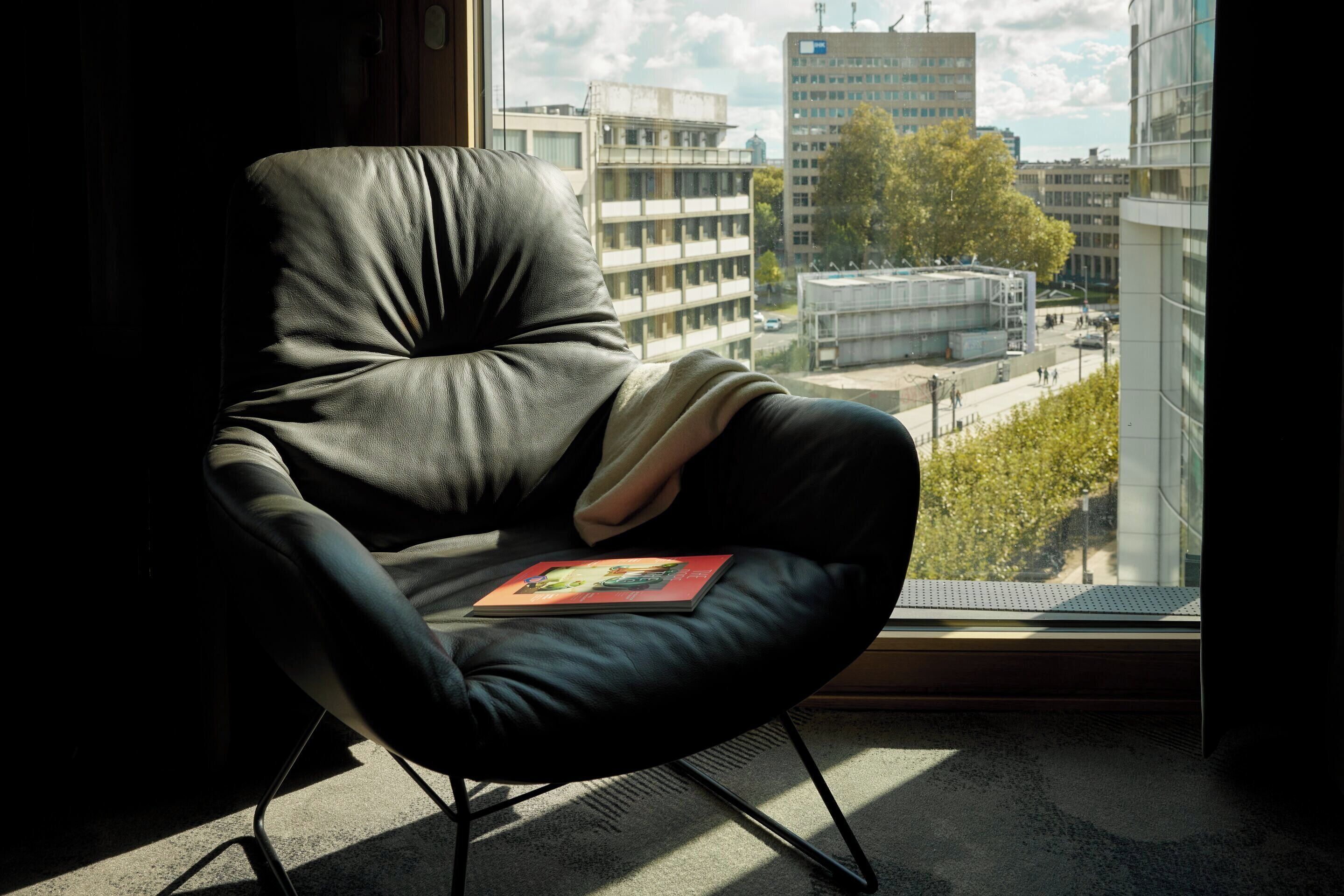 A modern chair with a cushion, positioned near a window overlooking a cityscape.