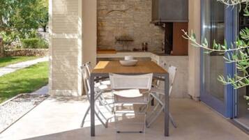 An outdoor dining area with a stone wall backdrop, a wooden table, and metal chairs.