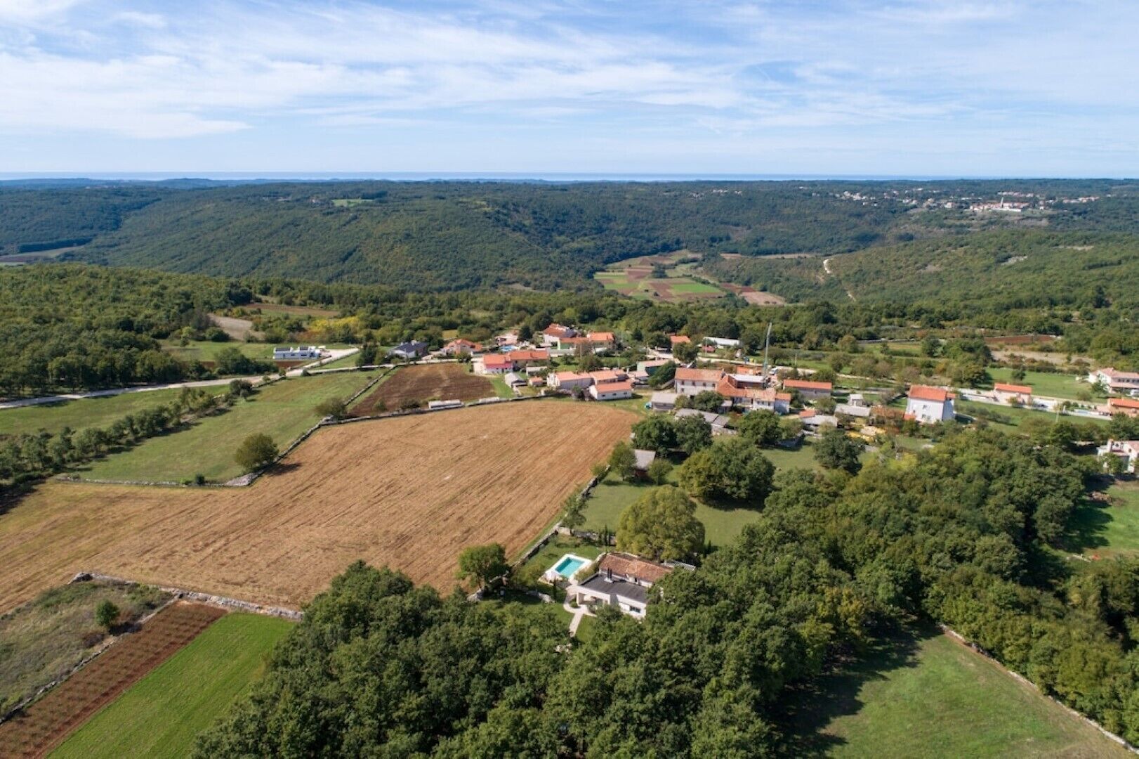 Vista aérea de un pueblo rural con casas, campos y una amplia zona abierta.