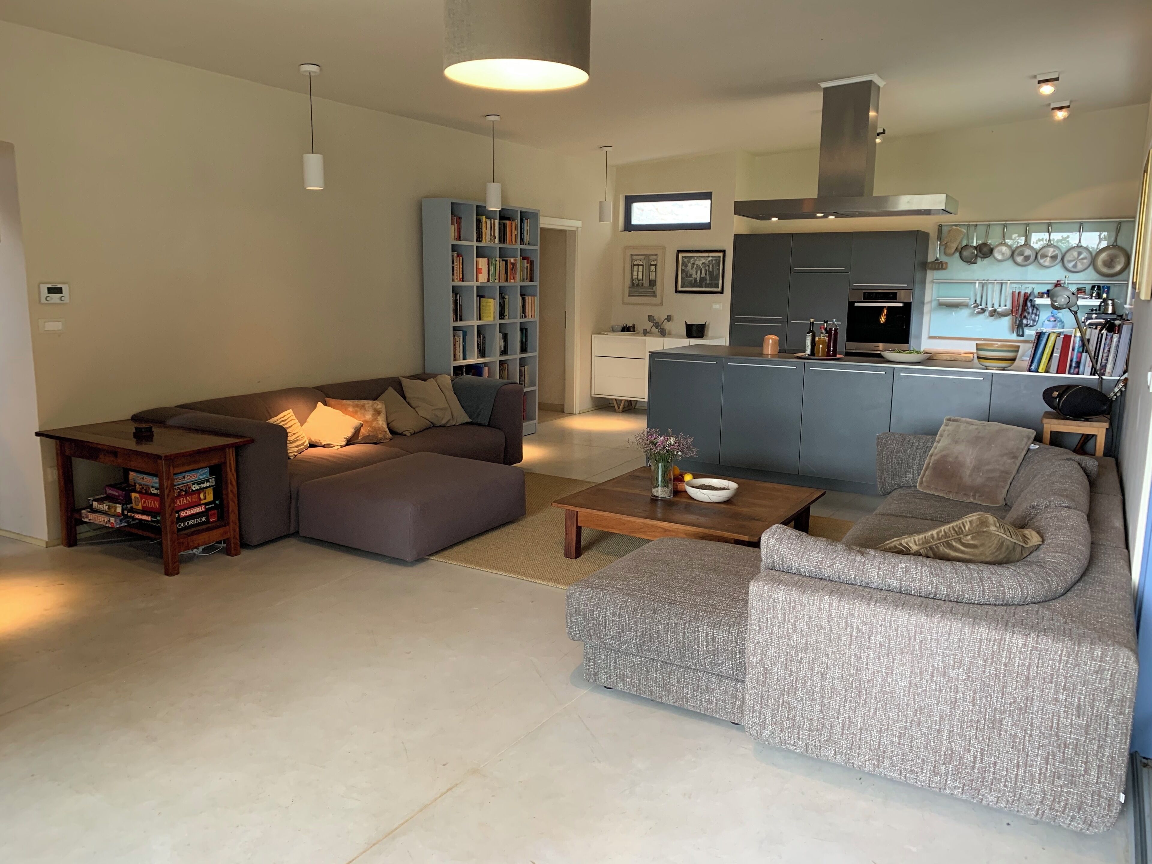 A modern living room with a sectional sofa, a coffee table, and a bookshelf.