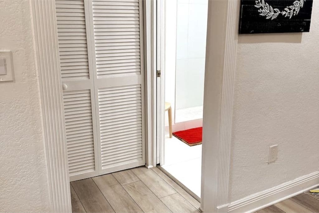 Ein Zimmer mit einer weißen, geschlossenen Tür, einer roten Matte im Eingangsbereich und einer an der Wand befestigten Dekoration.