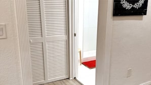 Ein Zimmer mit einer weißen, geschlossenen Tür, einer roten Matte im Eingangsbereich und einer an der Wand befestigten Dekoration.