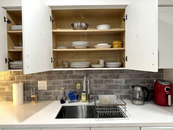 A kitchen with a built-in sink, a dish rack, and a coffee maker.