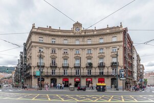 Un edificio storico con diversi piani, dettagli architettonici elaborati e una torre dell'orologio ben visibile.