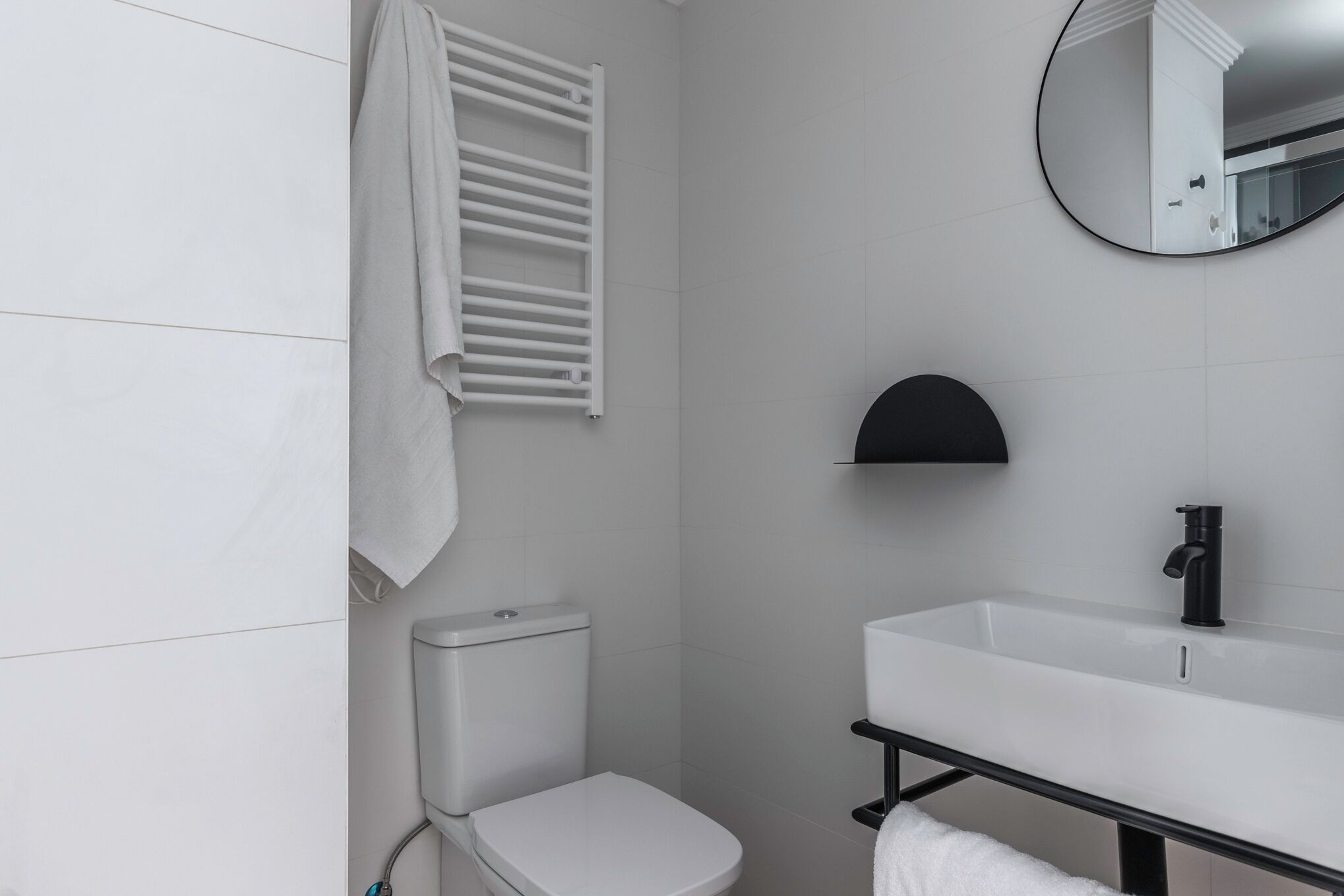 A modern bathroom with a toilet, a sink, and a towel rack.