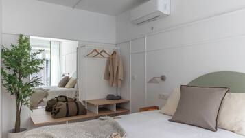 Um quarto moderno com uma cama, um espelho, um guarda-roupa, uma mesinha de cabeceira e um vaso de plantas.